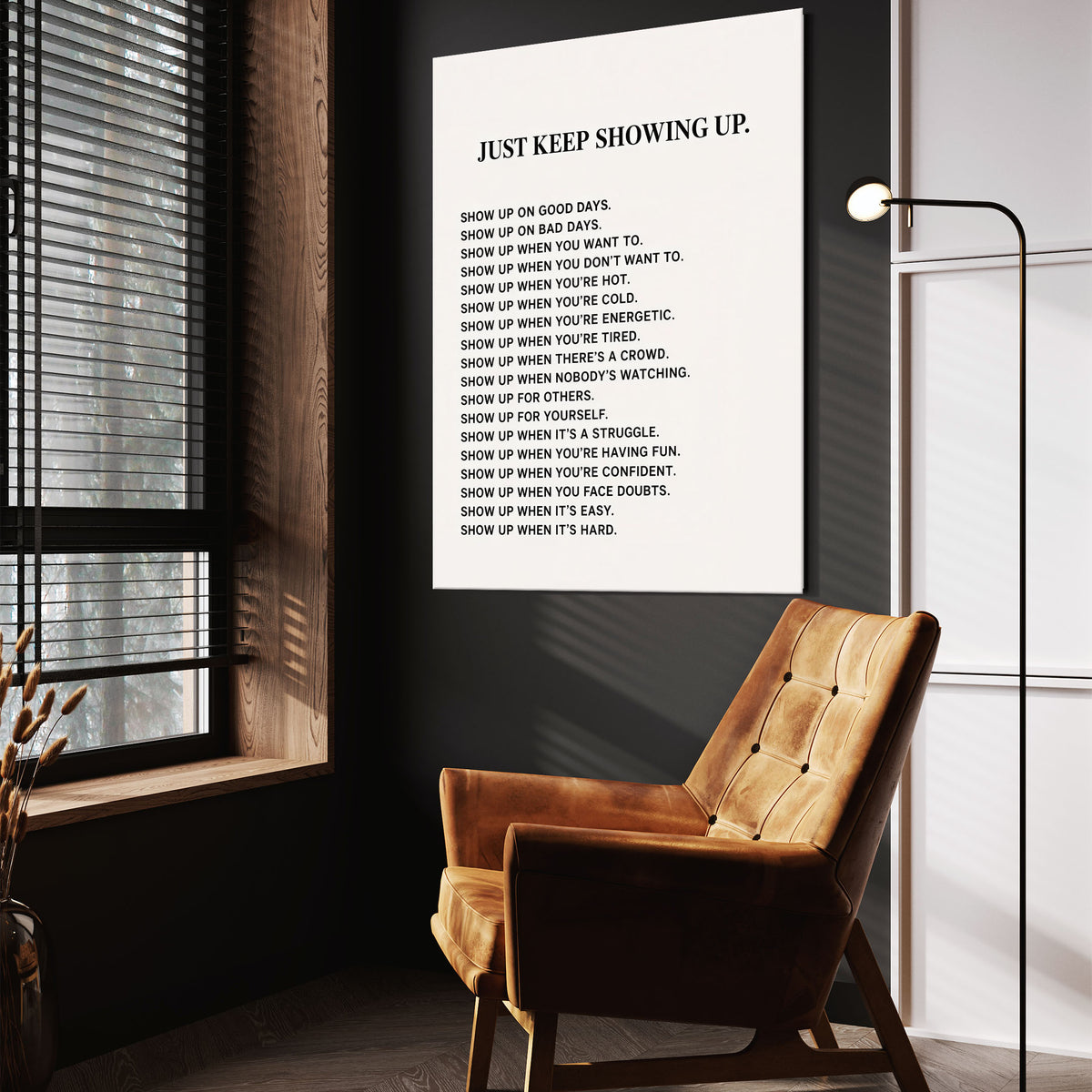 Just Keep Showing Up wall art above a tan chair in a dark reading corner