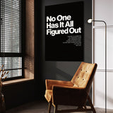 No One Has It All Figured Out wall art above a tan chair in a dark reading corner