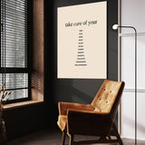 Take Care wall art above a wooden lounge chair in a dark room