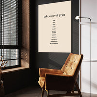 Take Care wall art above a wooden lounge chair in a dark room