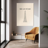 Take Care wall art above a tan chair in a bright room